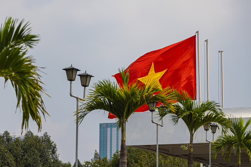 Ho Chi Minh City, Vietnam - November 07, 2022: Vietnamese national flag on the roof of the independence palace or reunification palace. The red flag with the yellow star, sign of the communist country