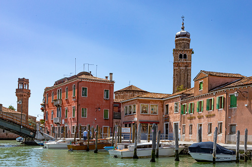 Murano, Italy - July 1, 2021: view to canal in Murano with facade of old traditional glass factory.