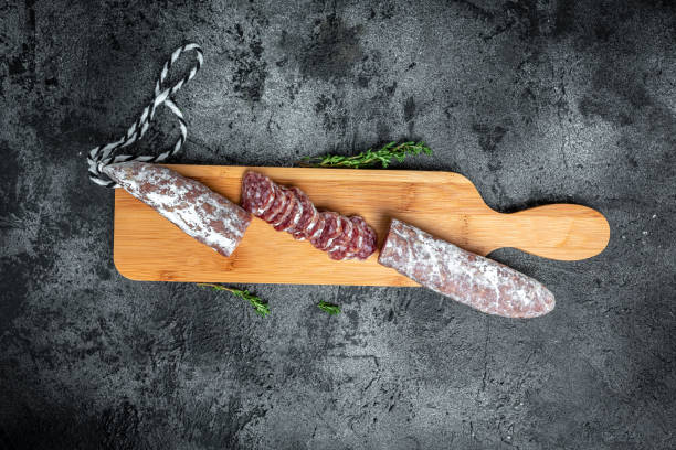 Fuet Salami cut in slices. Traditional Spanish sausage on wooden board. Fuets Catalan dry sausages. Top view stock photo