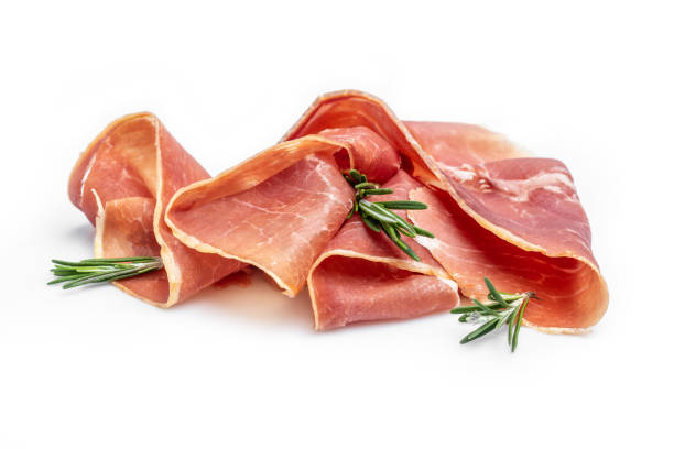 Italian prosciutto crudo or spanish jamon with rosemary, raw ham leg sliced isolated on white background stock photo