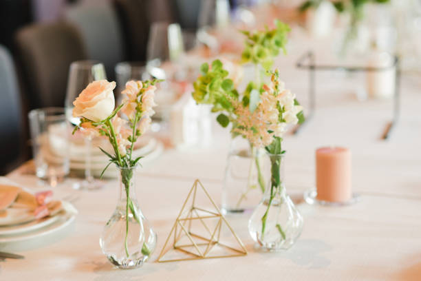 istock Table setting at the wedding reception. Floral compositions with beautiful flowers and greenery, candles, laying and plates on a decorated table. 1453783674