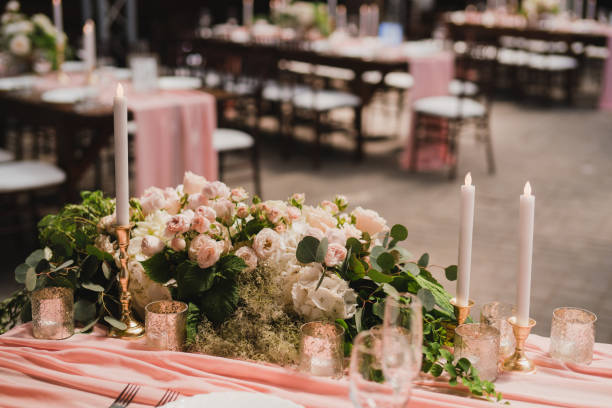 istock Table setting at the wedding reception. Floral compositions with beautiful flowers and greenery, candles, laying and plates on a decorated table. 1453783799