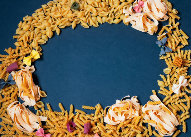 istock Frame made of different kinds of raw pasta on dark background. 1453785029