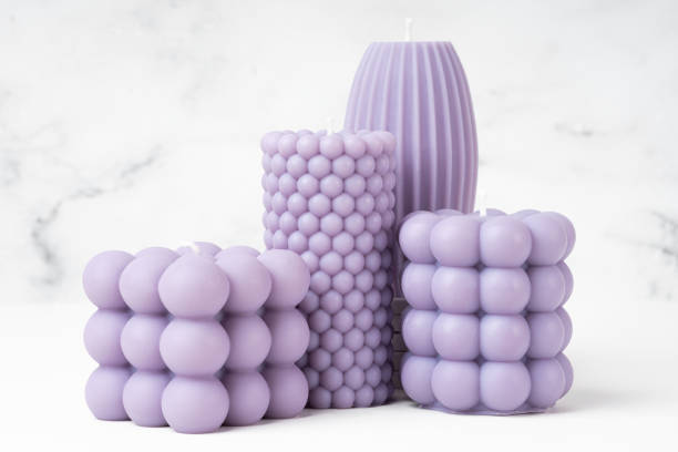 istock Handmade olive wax different forms lilac, purple color candle on a on the white marble table at home. Sustainability vegan candle, natural materials. Minimalistic, modern photo. Close up 1453787063