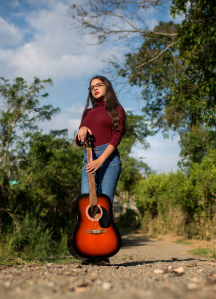 Young woman outdoors in her favorite hobbies, reading, enjoying and playing guitar.