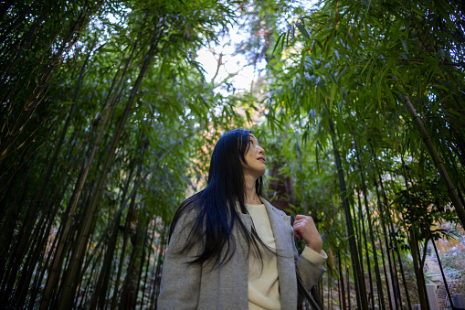 Low angle view of Japanese female tourist standing in bamboo grove