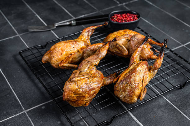 istock Grilled whole quails with herbs and spices. Black background. Top view 1453790545
