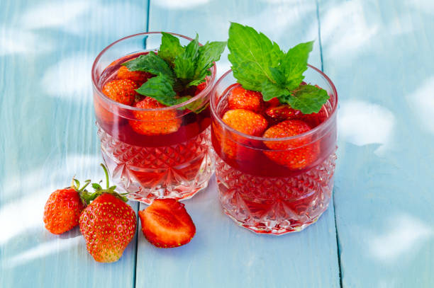istock Strawberries on the blue table and a fresh drinks with mint on sunny day 1453790703