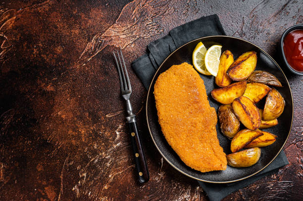 istock Roast pork schnitzel with fried potato, cooked meat steak. Dark background. Top view. Copy space 1453791722