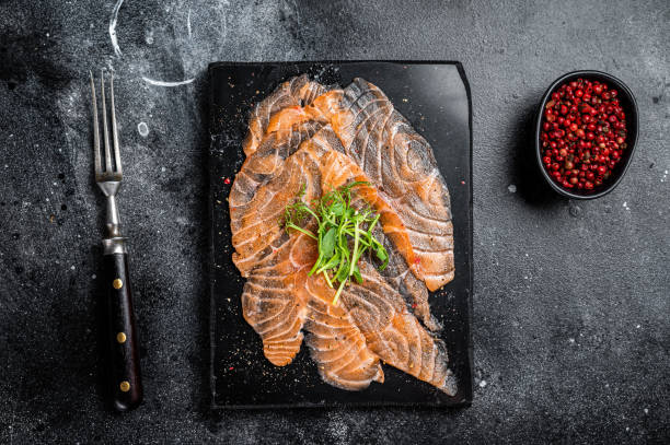 istock Salmon carpaccio with microgreens on marble board. Black background. Top view 1453791776