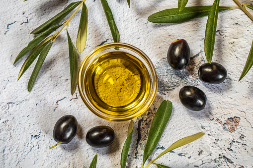 Olives and bottle of olive oil on wooden background, close up