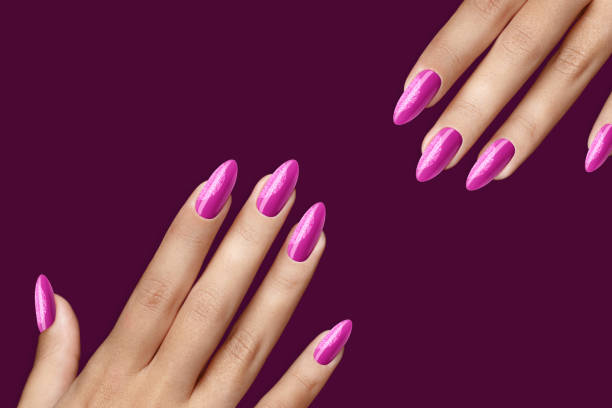 istock Pink with glitter fingernail points isolated on a purple background with nail polish 1453796813