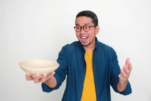 istock Adult Asian man looking at empty bowl that he hold with excited expression 1453797957