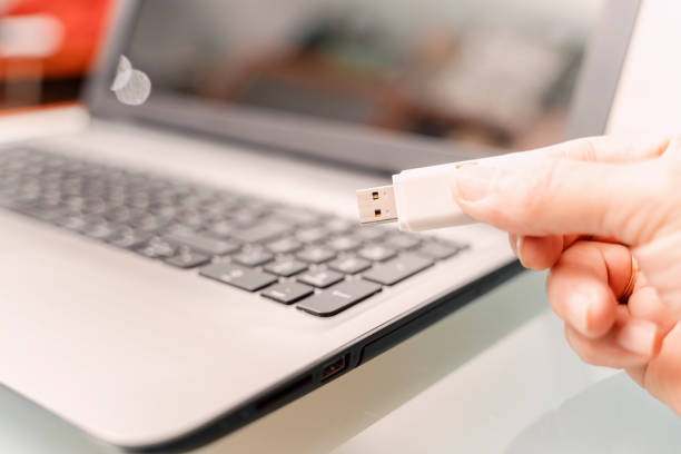 istock Close-up of a man using a USB stick connected to a laptop. The USB stick is a security risk 1453798250