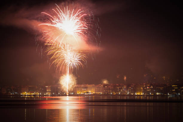 Fireworks above large residential area landscape at night. New Years Eve pyrotechnics at Thessaloniki, Greece seen from the city waterfront. stock photo