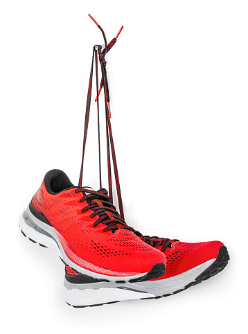 A pair of red running shoes hanging from a hook. 
Isolated on a white background.