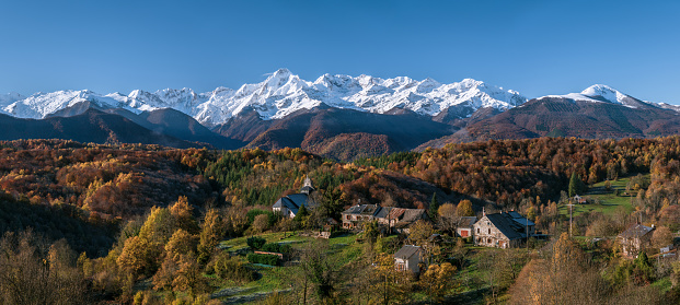 Mountain village in autumn with first snow on the peaks in the background