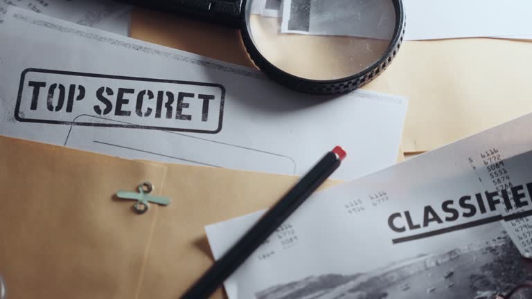 Slow pan across different top secret classified documents laid on office desk