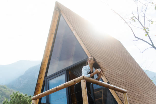 istock Young woman standing outside log cabin and holding drink 1453814018
