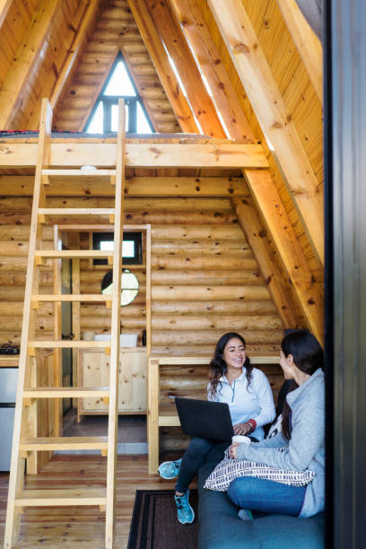 Two happy latin female friends talking inside of a log cabin.