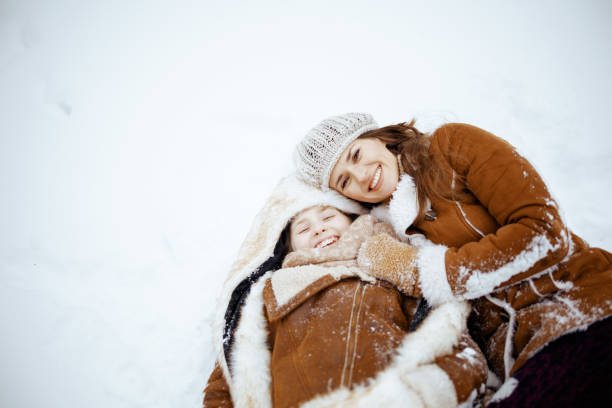 istock smiling modern mother and child laying in snow 1453816575