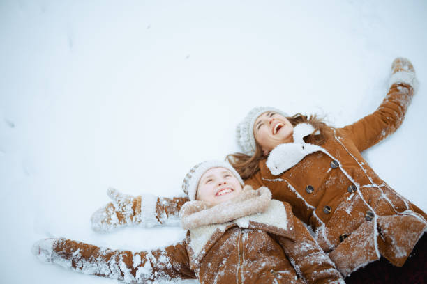 istock happy elegant mother and child making snow angel 1453816607