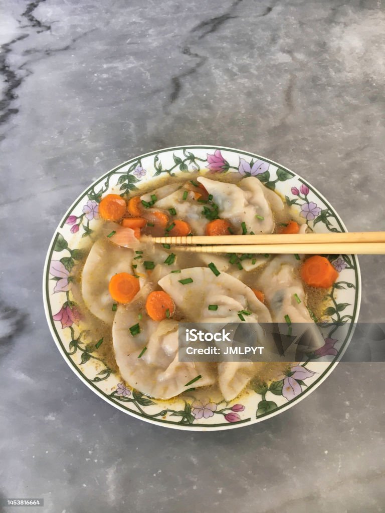 Chinese traditional dumplings Chinese dumplings in a plate with chopped carrots and chopsticks grabbing a dumpling Appetizer Stock Photo