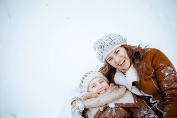 istock smiling elegant mother and child laying in snow 1453816921