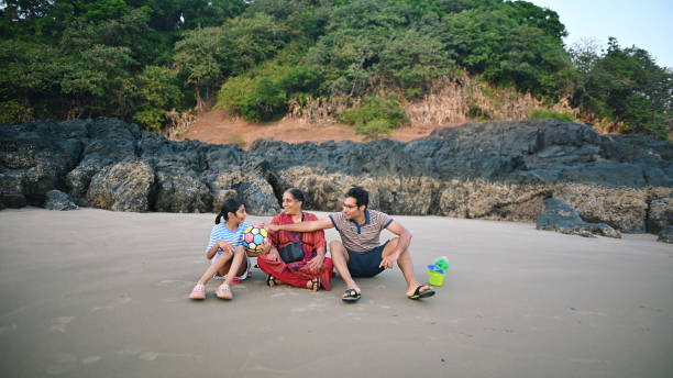 istock Multi-generation family sitting on the beach sand and talking to each other 1453817434