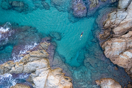 Landscape of aerial top view from drone of a swimmer in open water with wetsuit and buoy