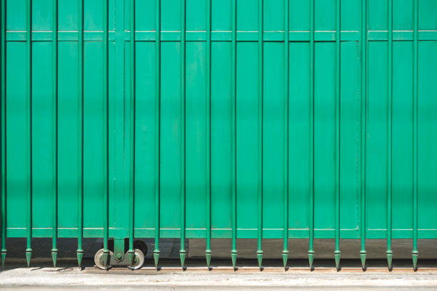 Front view of metal green automatic sliding gate door with spike pattern in front of modern house