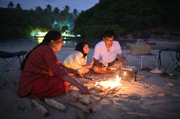 istock Multi-generation family sitting around a campfire and having a Barbeque on the beach 1453818553