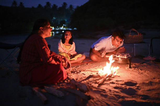 istock Three generation family sitting around a campfire and having a Barbeque on the beach 1453818601