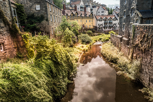 Old village in the heart of Edinburgh with iconic houses and tranquil stream.