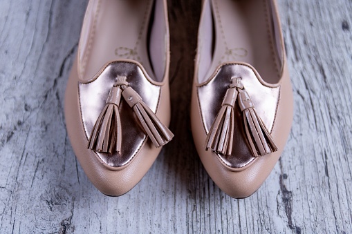 A closeup shot of women's cream flat shoes, ballet flats on a wooden background