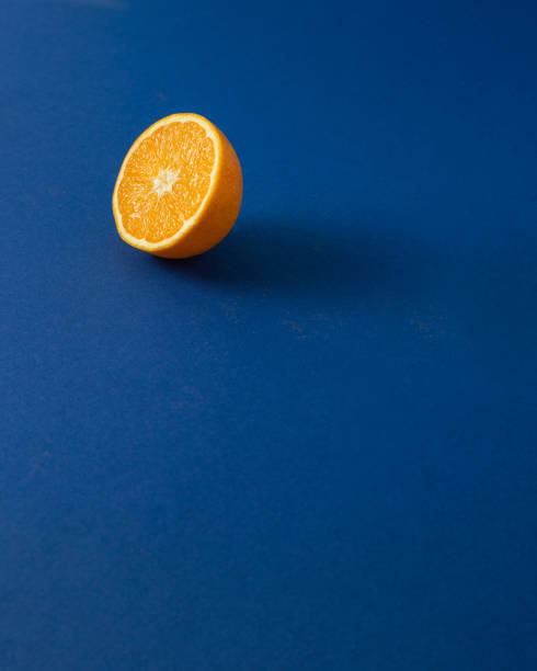 istock orange cut in half against royal blue background.Creative summer concept with copy space. 1453822698