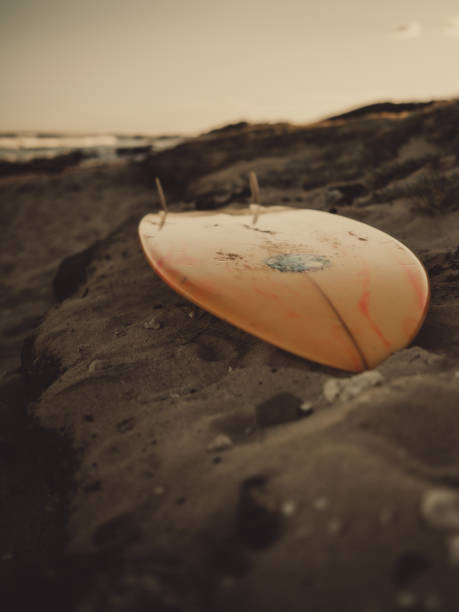 istock Vertical shot of an orange surfboard on a beach 1453827034