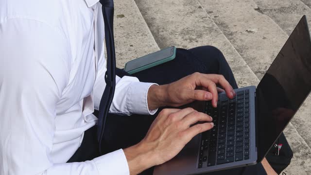 Young businessman is working outdoors with his computer.