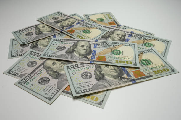 istock Pile of 100 US dollar bills on a white surface 1453831091