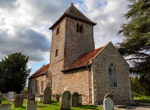 The parish church of All Saints in the small hamlet of Newton by Castle Acre in Norfolk, eastern England, with part of the graveyard. It was probably once cruciform and has been considerably altered over the centuries, although much of the church is obviously Saxon or early Norman.