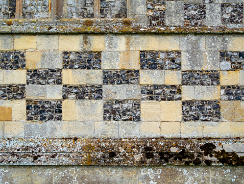 Part of a medieval church wall in Norfolk, Eastern England, with a checkerboard pattern using blocks of stone alternating with rectangles of knapped flints.