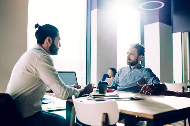 istock Colleagues in formal wear talking in open office 1453832902