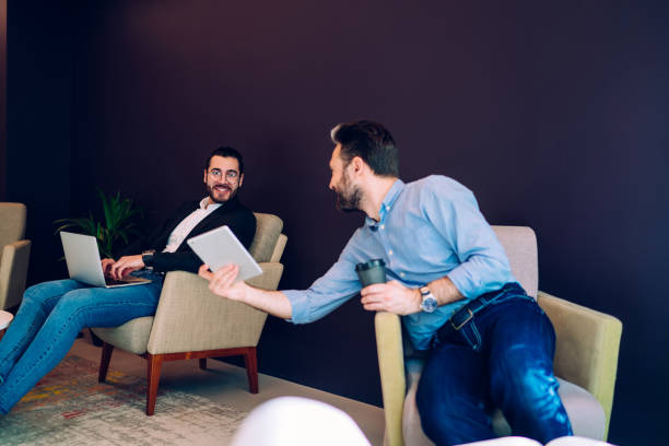 istock Cheerful coworkers communicating and sitting in armchairs 1453832964