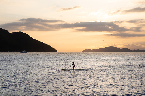 Girl practicing stand up paddle during the late afternoon in Santos bay.