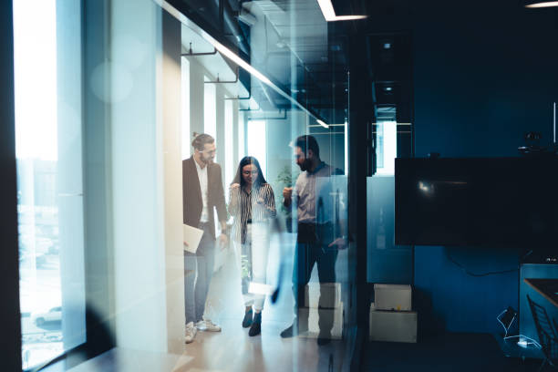 istock Business colleagues talking in corridor through glass wall 1453833008