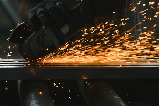 Unrecognizable metal worker grinding metal with an electric saw