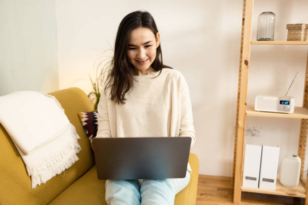 istock Smiling woman with computer at home 1453839700