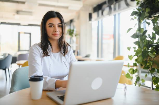 istock Freelance, business and e-commerce concept. Creative enthusiastic female journalist writing new article, typing on laptop, smiling, write-down project ideas, sit cafe, drink coffee working remote 1453840558