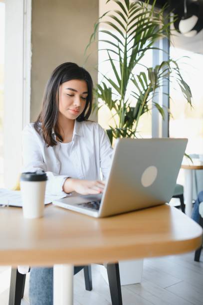 istock Freelance, business and e-commerce concept. Creative enthusiastic female journalist writing new article, typing on laptop, smiling, write-down project ideas, sit cafe, drink coffee working remote 1453840621