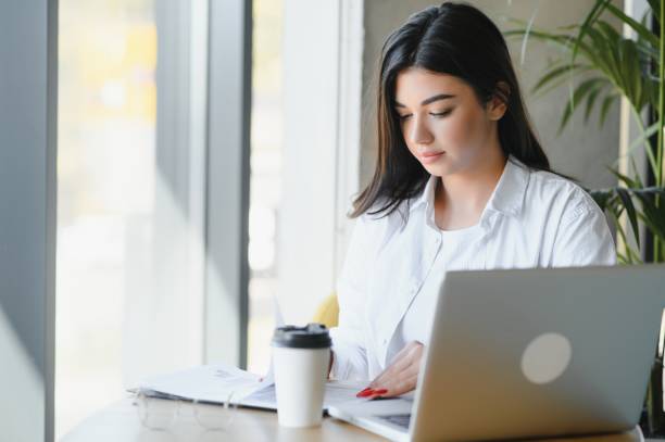istock Joyful girl student studying online at cafe, using laptop and earphones, empty space 1453840797